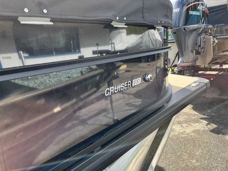 Slide: The Image of 2025 Harris Cruiser 230 boat with Yamaha engine, parked outdoors. - 5