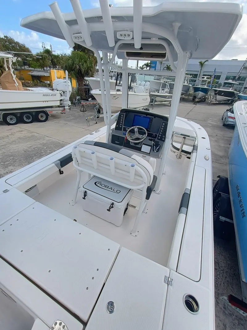 Slide: The Image of 2025 Robalo 246 Cayman boat with center console and seating, docked at a marina. - 6