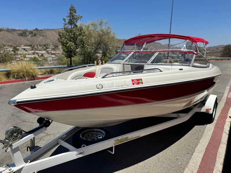 Slide: The Image of 2006 Stingray 195 LR boat with red canopy on a trailer, parked outdoors. - 3