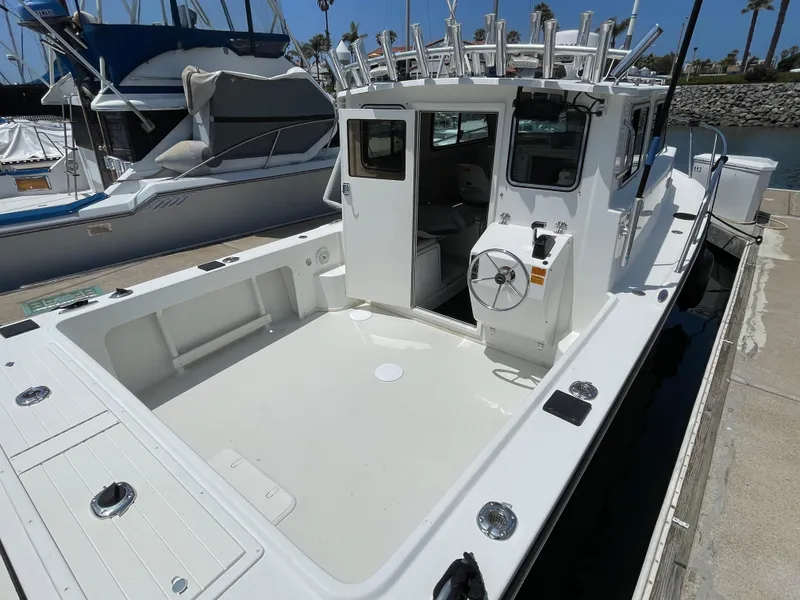 Slide: The Image of 2016 Parker 2530 Extended Sport Cabin boat docked, showcasing spacious deck and cabin entrance. - 12