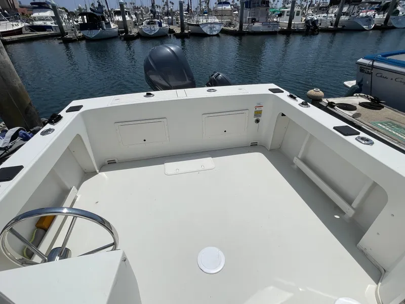 Slide: The Image of 2016 Parker 2530 Extended Sport Cabin boat interior at marina, featuring spacious deck and steering wheel. - 17