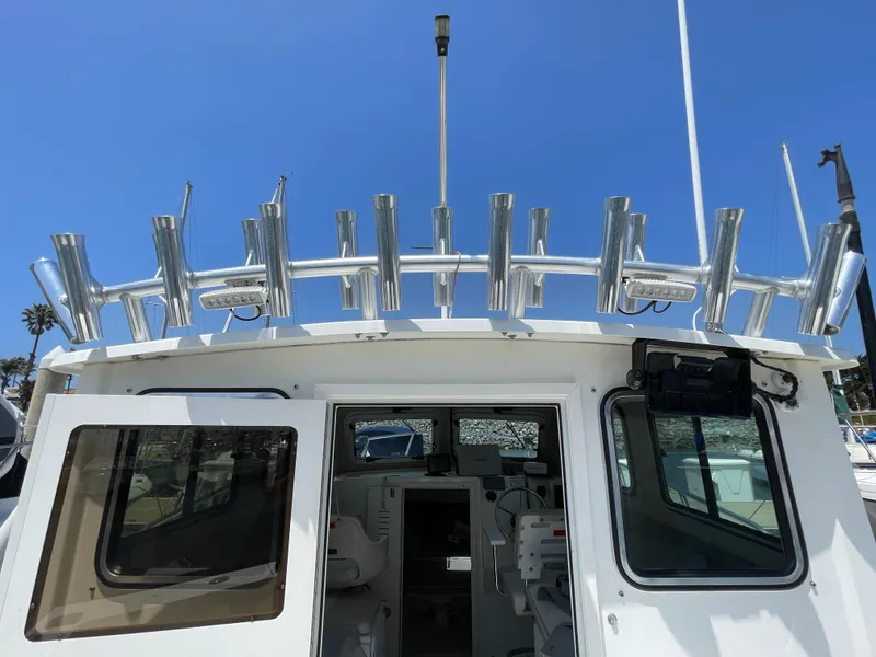 Slide: The Image of 2016 Parker 2530 Extended Sport Cabin boat with rod holders, viewed from the rear. - 19