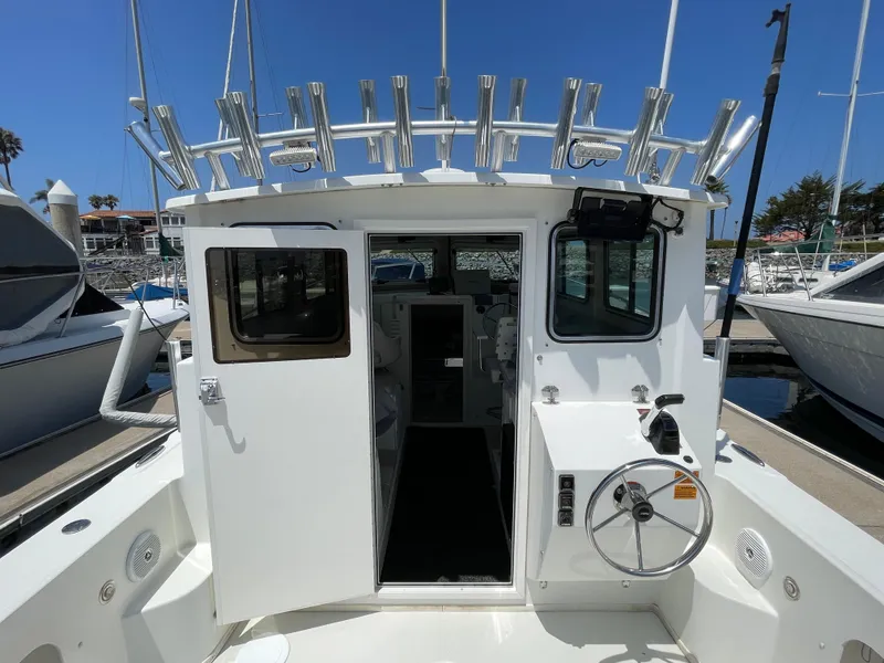 Slide: The Image of 2016 Parker 2530 Extended Sport Cabin boat at marina, open cabin door, steering wheel visible. - 20