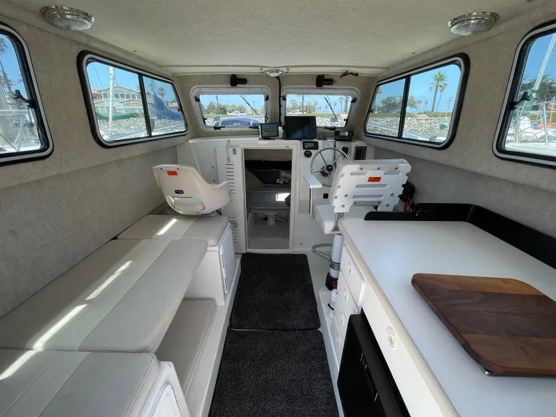 Slide: The Image of Interior of a 2016 Parker 2530 Extended Sport Cabin boat, featuring seating and helm. - 21