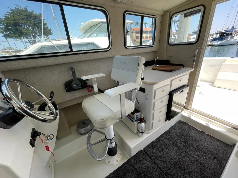 Slide: The Image of Interior of 2016 Parker 2530 Extended Sport Cabin with helm, seating, and storage. - 25