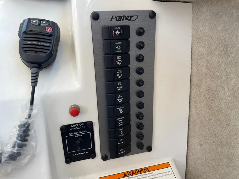 Slide: The Image of Control panel of a 2016 Parker 2530 Extended Sport Cabin boat with switches and microphone. - 31