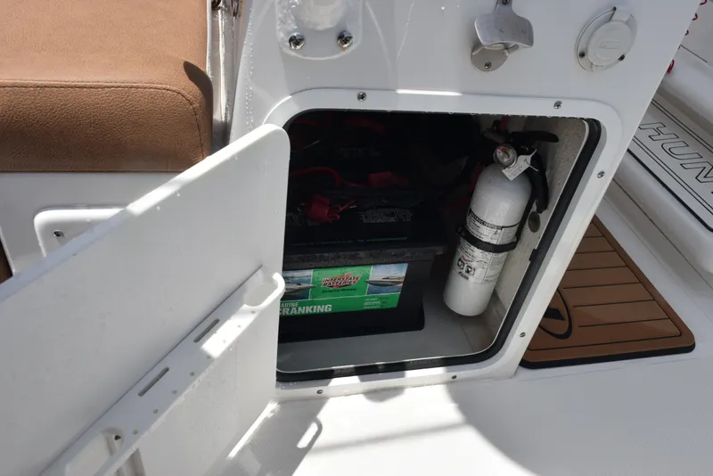 Slide: The Image of Open storage compartment on 2021 Sea Hunt Ultra 255 SE with battery and fire extinguisher. - 22