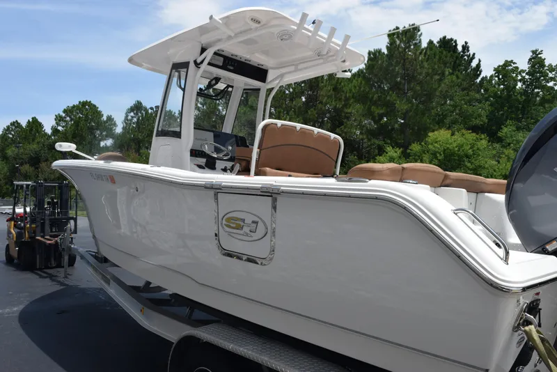 Slide: The Image of 2021 Sea Hunt Ultra 255 SE boat on trailer, parked outdoors with trees in background. - 6
