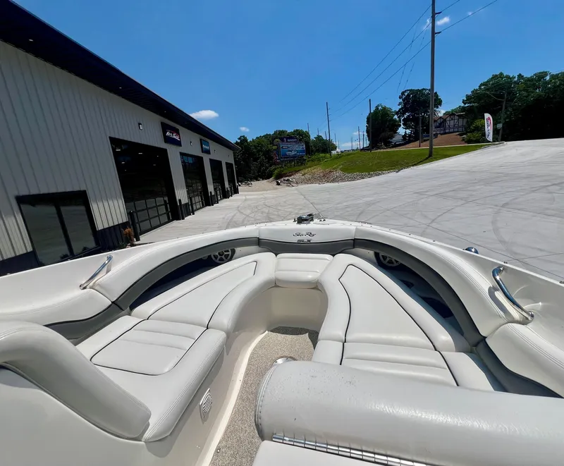 Slide: The Image of 2007 Sea Ray 290 SLX boat interior with white seating, parked near a building. - 18