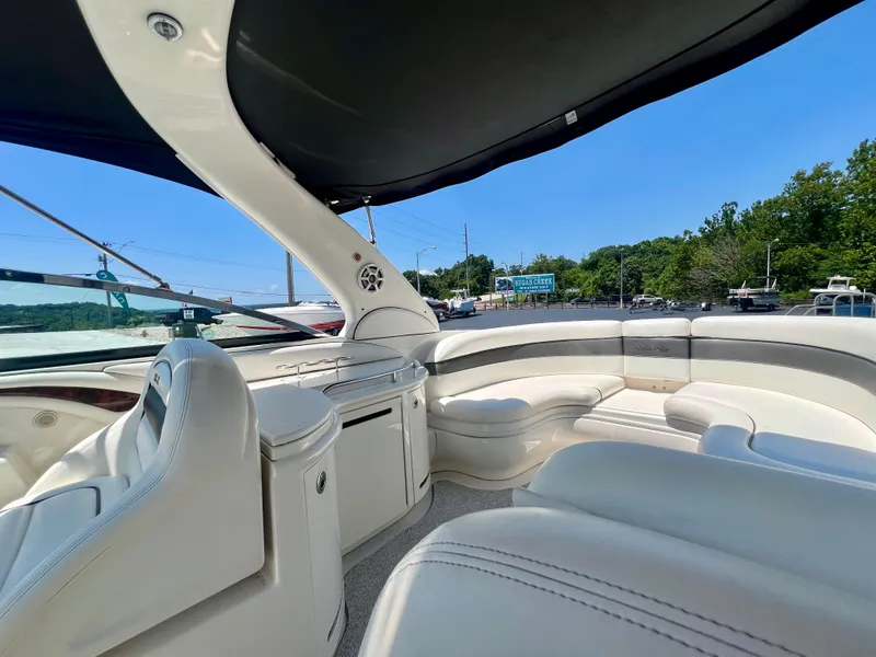 Slide: The Image of 2007 Sea Ray 290 SLX boat interior with white seating and canopy, parked near a marina. - 6