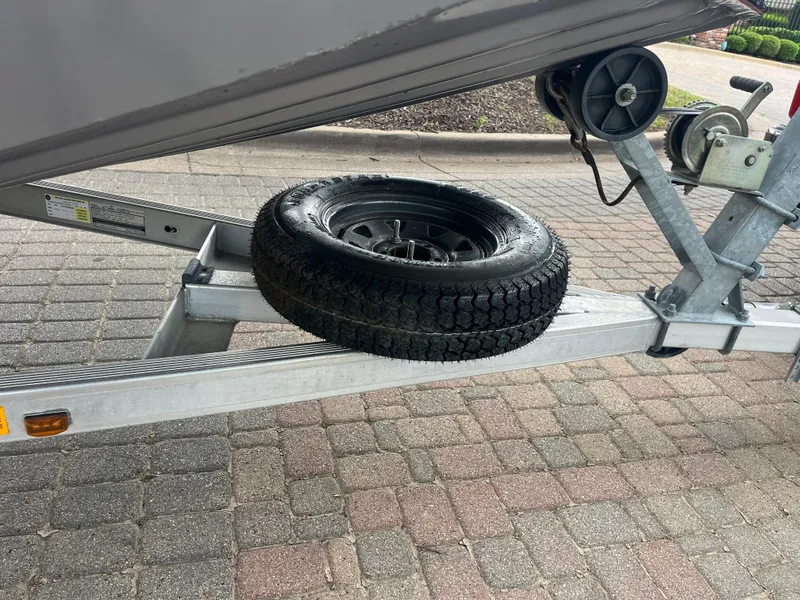 Slide: The Image of 2012 Alumacraft Pro 165 boat trailer with spare tire on a paved surface. - 15