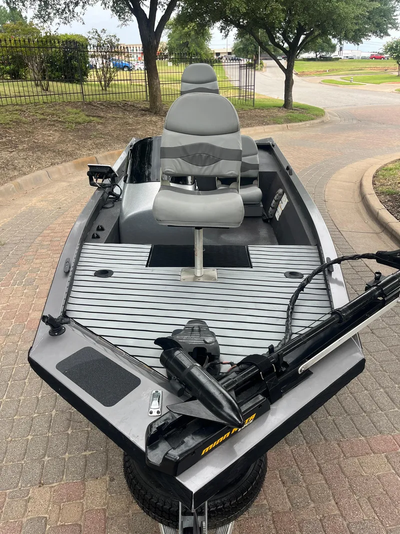 Slide: The Image of 2012 Alumacraft Pro 165 boat with seating and trolling motor, parked on a paved area. - 18