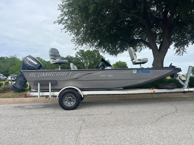 Slide: The Image of 2012 Alumacraft Pro 165 fishing boat on trailer, parked under a tree. - 28