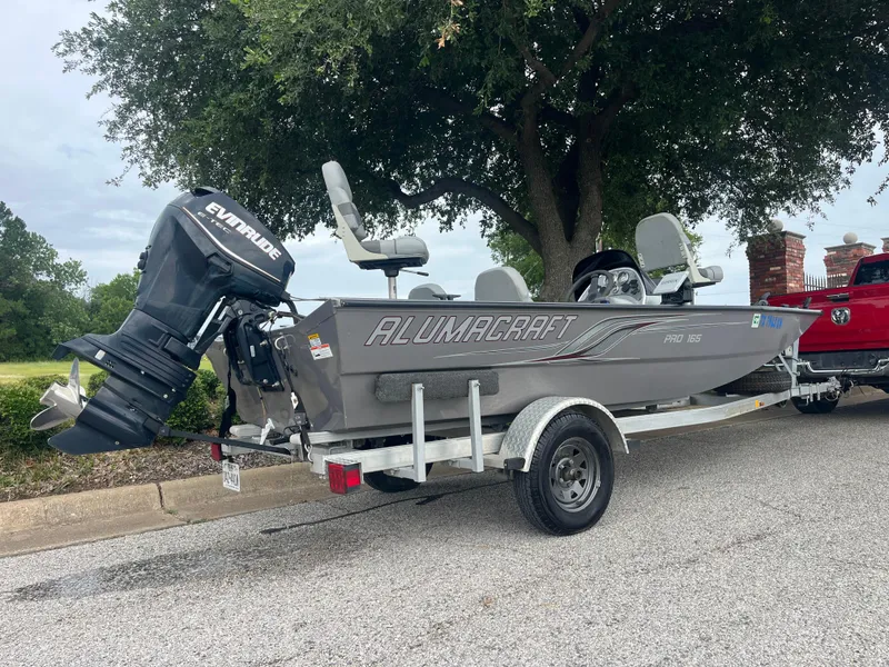 Slide: The Image of 2012 Alumacraft Pro 165 boat on trailer with Evinrude motor, parked outdoors. - 29