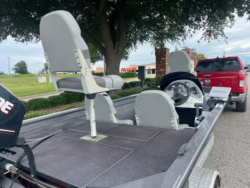 Slide: The Image of 2012 Alumacraft Pro 165 boat interior with seating and steering, parked near a red truck. - 31