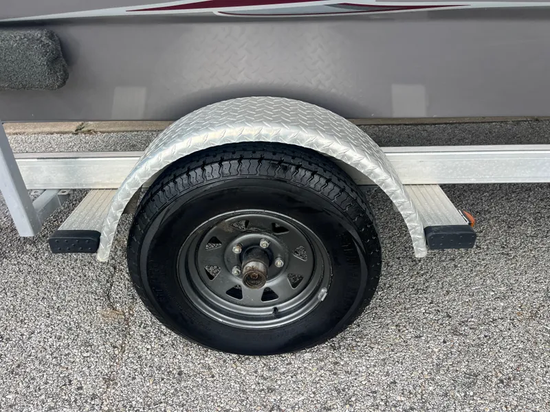 Slide: The Image of 2012 Alumacraft Pro 165 trailer wheel with diamond plate fender on gravel surface. - 36