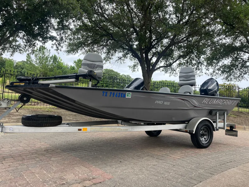 Slide: The Image of 2012 Alumacraft Pro 165 boat on trailer, parked outdoors under trees. - 4