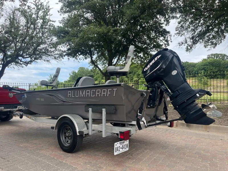 Slide: The Image of 2012 Alumacraft Pro 165 boat on trailer with outboard motor, parked outdoors. - 6