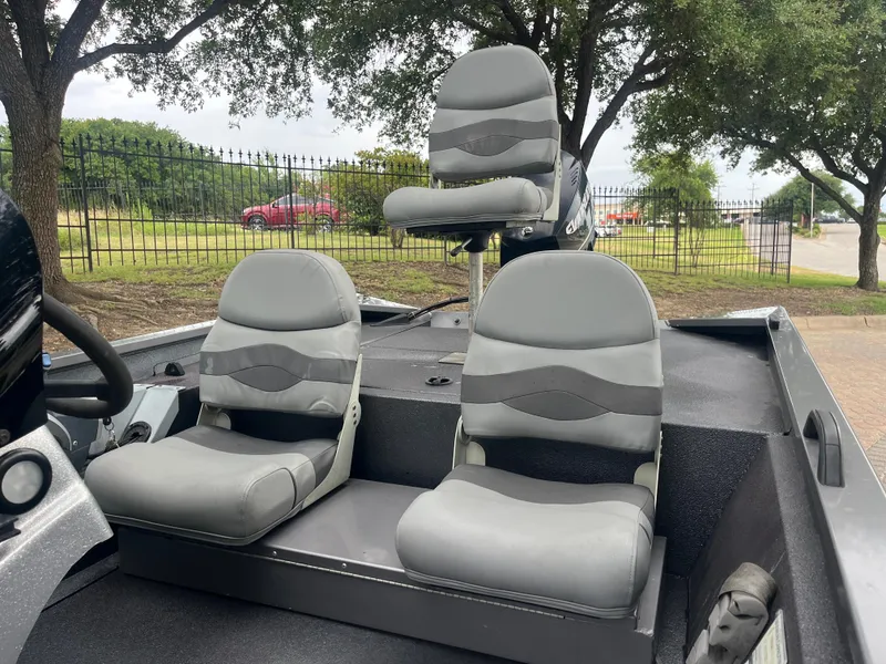 Slide: The Image of 2012 Alumacraft Pro 165 boat interior with three gray seats, parked outdoors. - 9