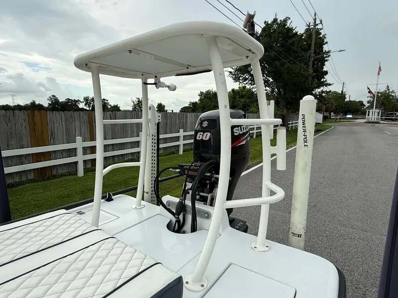 Slide: The Image of 2014 Bossman TailSpotter boat with Suzuki 60 engine and Power-Pole, parked near a fence. - 17
