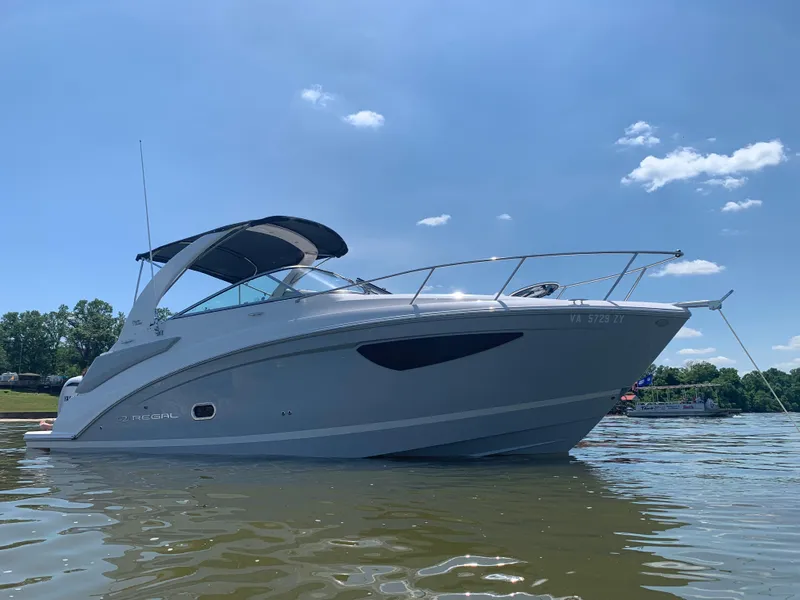 The Image of 2022 Regal 26 XO boat with Yamaha engine on a trailer, surrounded by trees. - 0