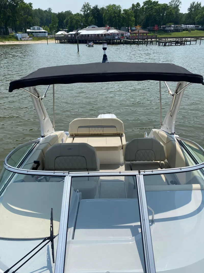 Slide: The Image of 2022 Regal 26 XO boat interior with beige seating and steering wheel on water. - 10