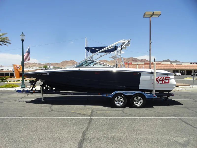 Slide: The Image of 2006 MasterCraft X-45 boat on trailer in parking lot, clear sky background. - 1