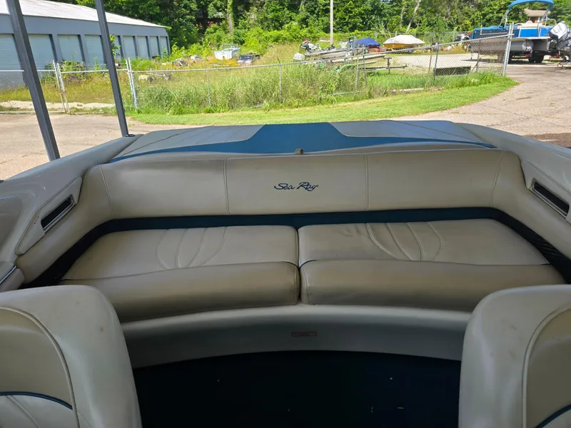 Slide: The Image of 1998 Sea Ray 210br boat interior with beige seating, outdoor storage background. - 4
