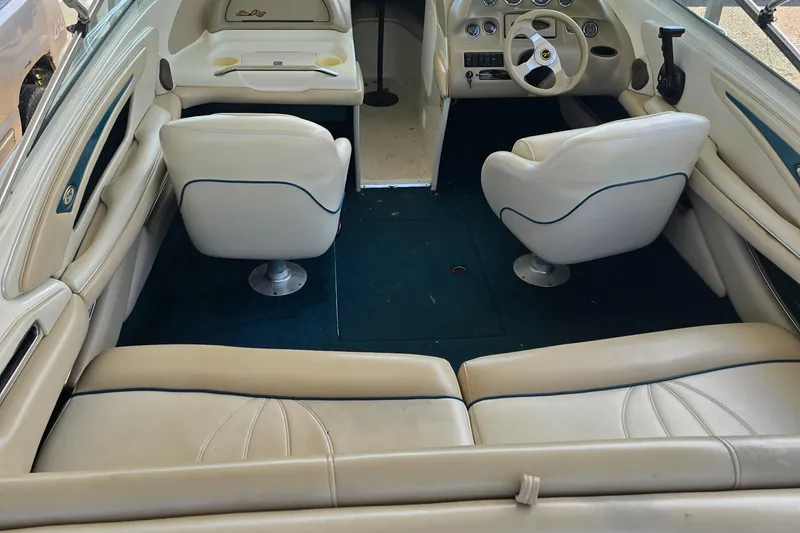 Slide: The Image of Interior of a 1998 Sea Ray 210br boat with white seating and blue carpet. - 5
