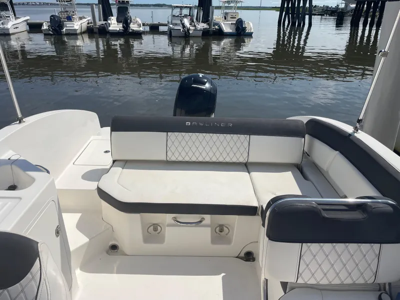 Slide: The Image of 2023 Bayliner DX 2200 boat interior with cushioned seating at a marina. - 7