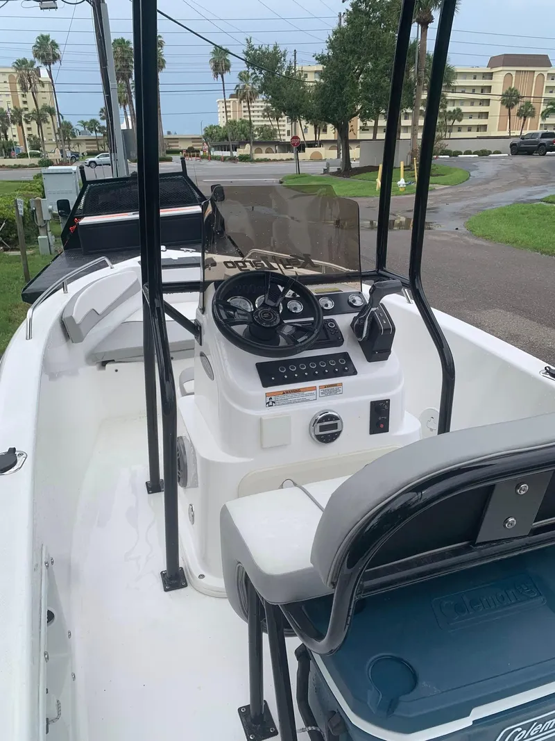 Slide: The Image of 2015 Key Largo 180 Center Console boat with steering wheel and controls, parked near buildings. - 24