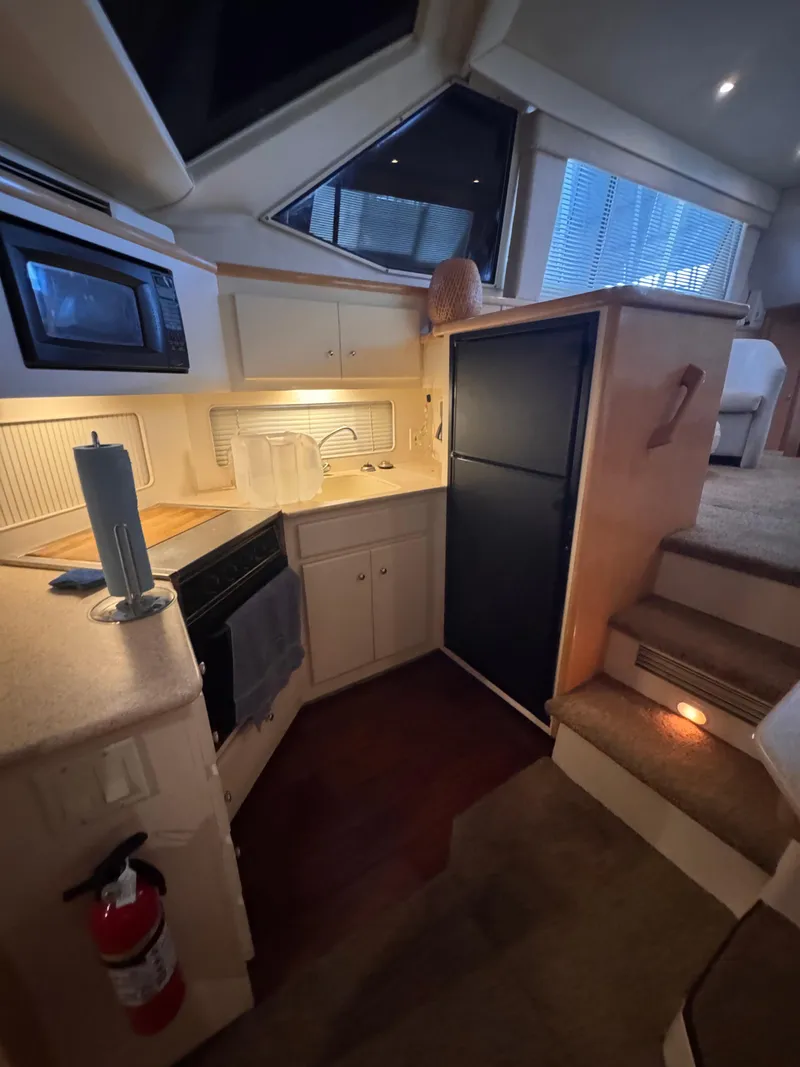Slide: The Image of 1998 Carver 405 Aft Cabin kitchen with microwave, fridge, and stairs. - 12