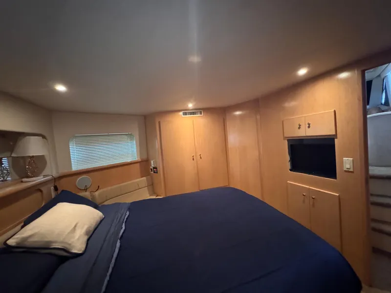 Slide: The Image of 1998 Carver 405 Aft Cabin bedroom with blue bedding and wooden cabinetry. - 19