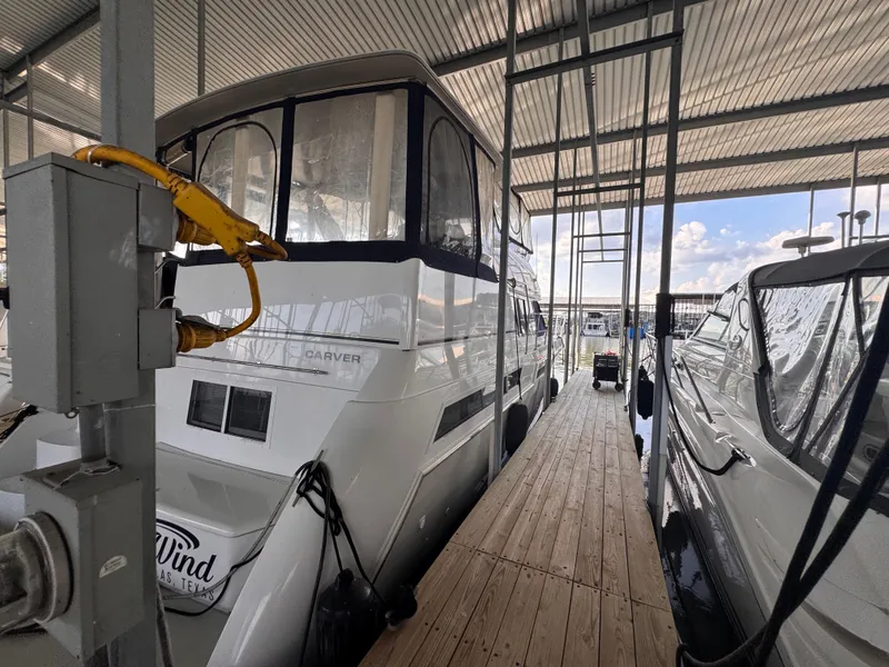 Slide: The Image of 1998 Carver 405 Aft Cabin yacht docked in a marina under a covered structure. - 2