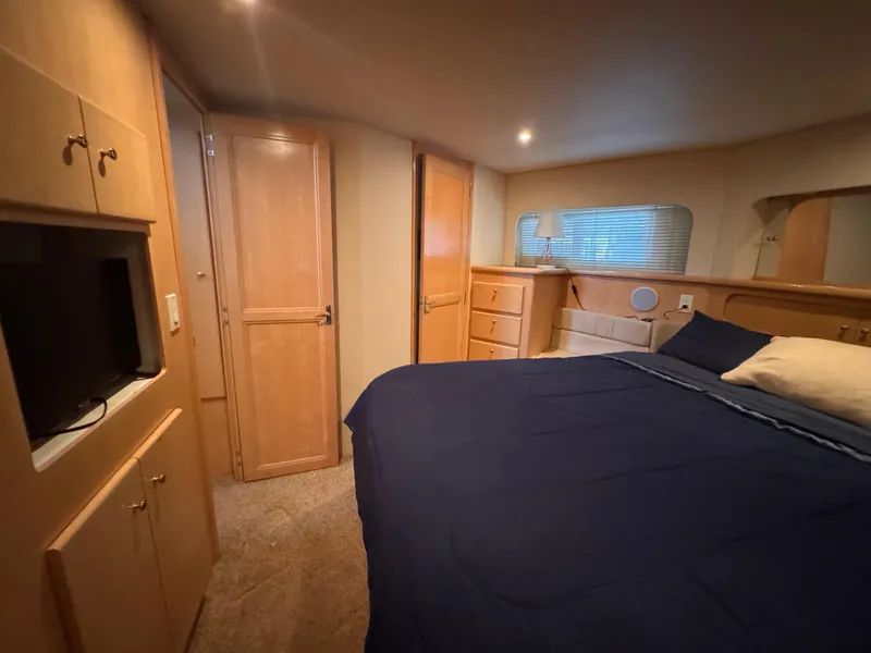 Slide: The Image of 1998 Carver 405 Aft Cabin bedroom with blue bedding, wooden cabinets, and a small TV. - 20