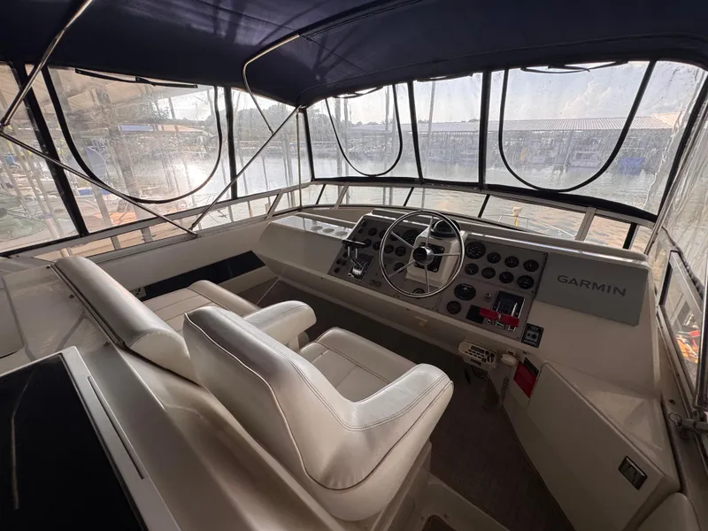 Slide: The Image of 1998 Carver 405 Aft Cabin helm with Garmin navigation, featuring dual seats and panoramic windows. - 24