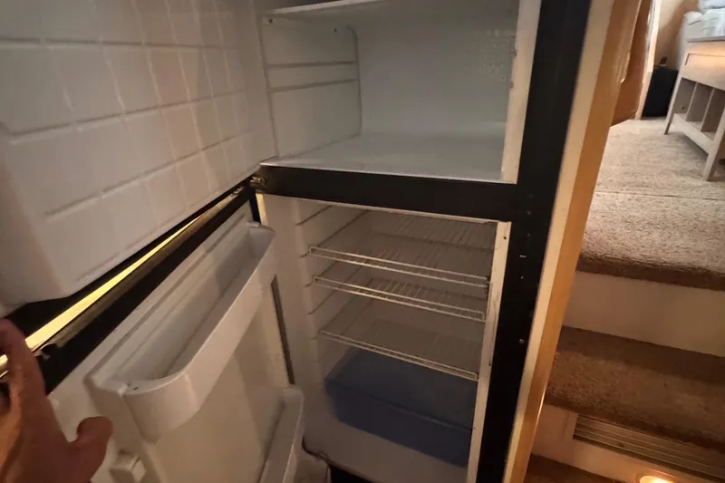 Slide: The Image of Open refrigerator inside 1998 Carver 405 Aft Cabin yacht, showing empty shelves and freezer. - 29