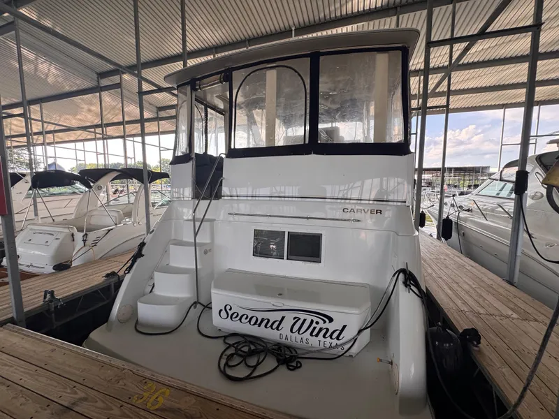 Slide: The Image of 1998 Carver 405 Aft Cabin yacht docked, featuring "Second Wind" signage, under a covered marina. - 3