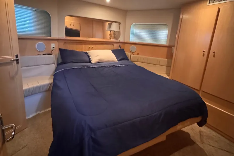 Slide: The Image of 1998 Carver 405 Aft Cabin bedroom with blue bedding and wooden interior. - 31