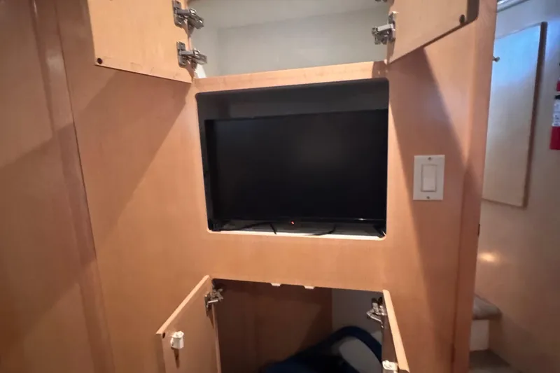 Slide: The Image of 1998 Carver 405 Aft Cabin interior with built-in TV and open wooden cabinets. - 33