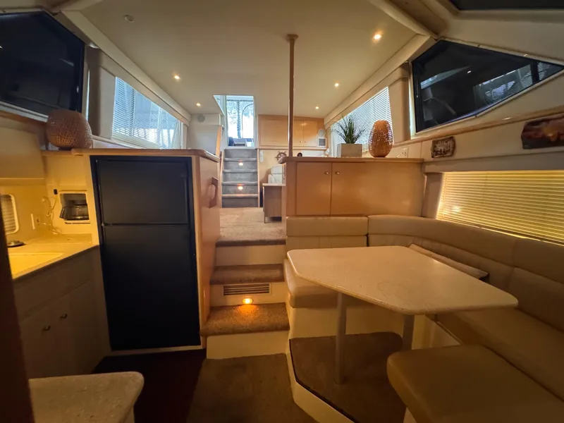 Slide: The Image of 1998 Carver 405 Aft Cabin interior with dining area, kitchenette, and stairs to upper deck. - 6