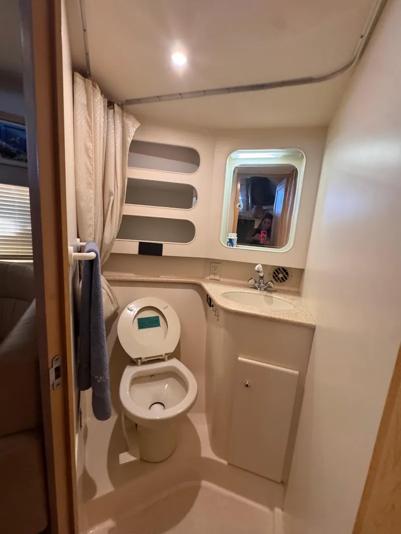 Slide: The Image of 1998 Carver 405 Aft Cabin bathroom with toilet, sink, mirror, and storage shelves. - 8