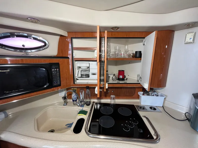 Slide: The Image of 1999 Sea Ray 400 Sundancer kitchen with microwave, sink, stove, and open cabinets. - 16