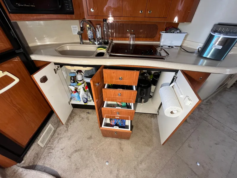 Slide: The Image of 1999 Sea Ray 400 Sundancer kitchen with open cabinets and drawers, showcasing storage and appliances. - 17