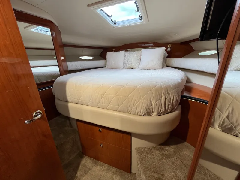 Slide: The Image of 1999 Sea Ray 400 Sundancer cabin with cozy bed and wooden interior. - 20