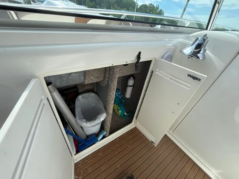 Slide: The Image of 1999 Sea Ray 400 Sundancer storage compartment with trash bin and cleaning supplies. - 42