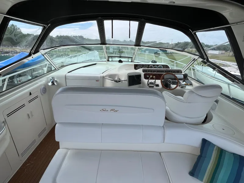 Slide: The Image of 1999 Sea Ray 400 Sundancer yacht interior with helm, white seating, and striped pillow. - 44