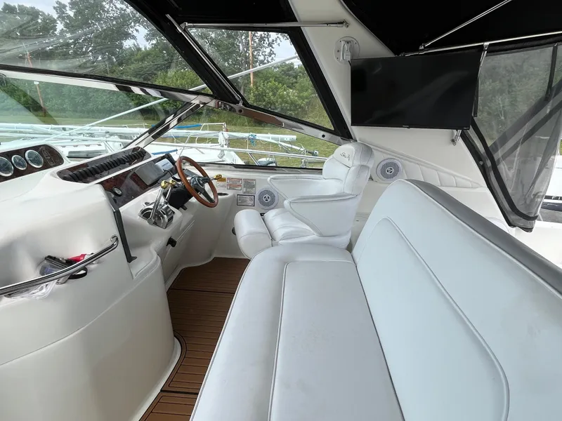 Slide: The Image of 1999 Sea Ray 400 Sundancer helm with white seating, wooden steering wheel, and modern controls. - 47