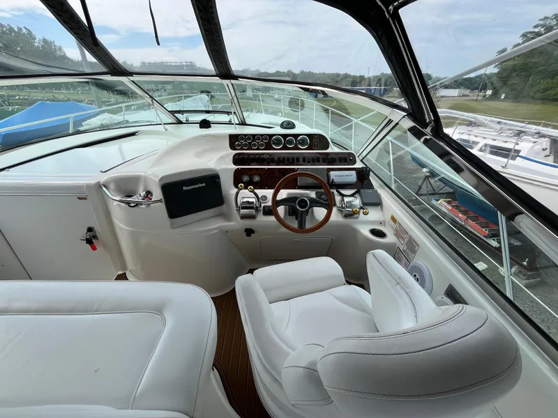Slide: The Image of 1999 Sea Ray 400 Sundancer helm with white seating and wood-accented steering wheel. - 49