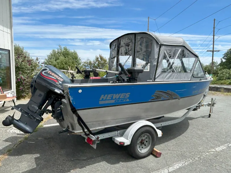 Slide: The Image of 1999 Hewescraft Sea Runner 179 boat with Evinrude motor on trailer, parked outdoors. - 6